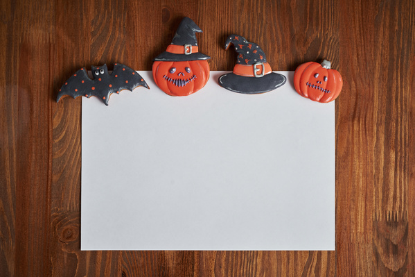 Different Black And Orange Halloween Cookies Are on Edge of Sheet of Paper